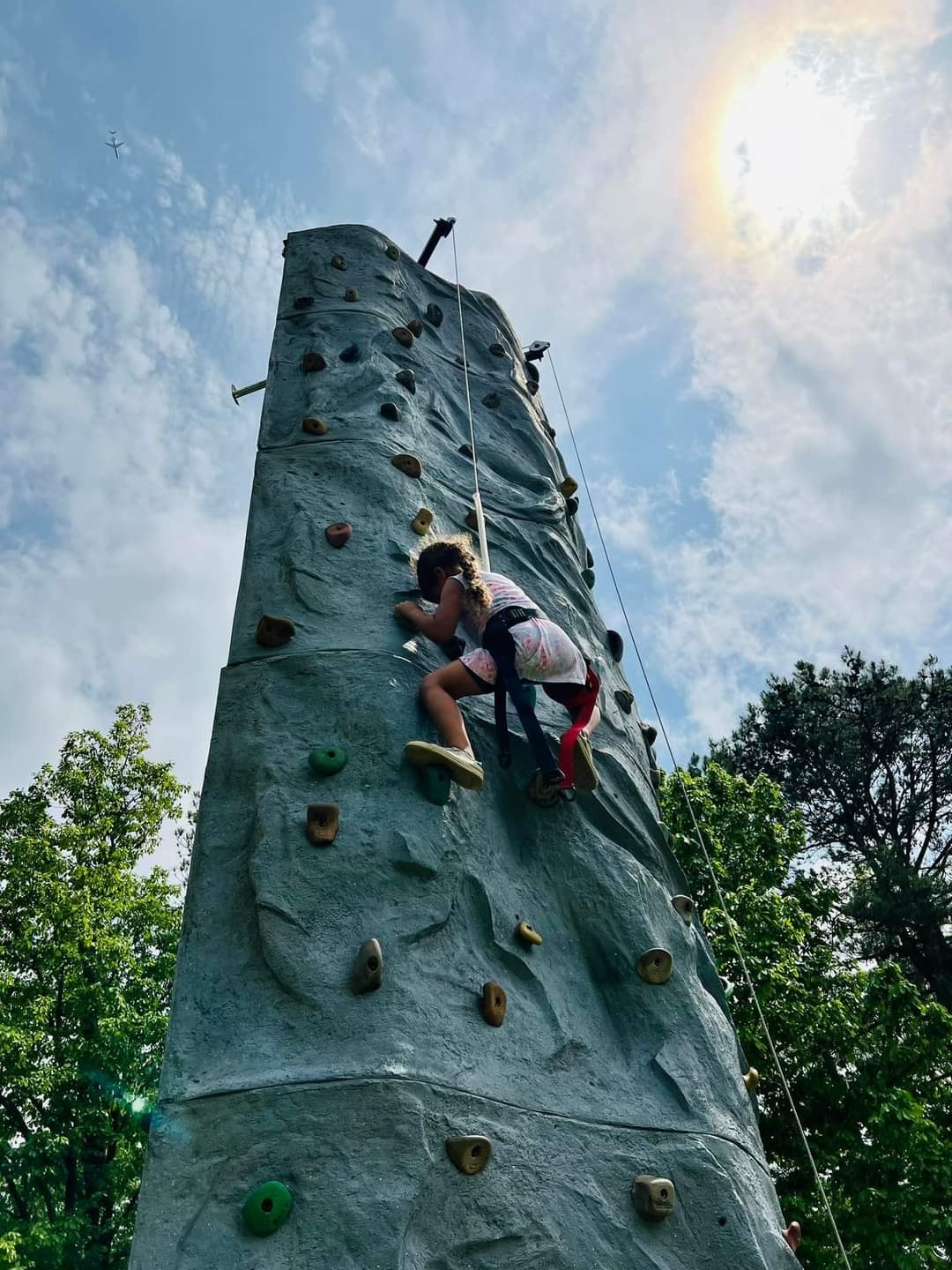 Girl scaling outdoor rock climbing wall